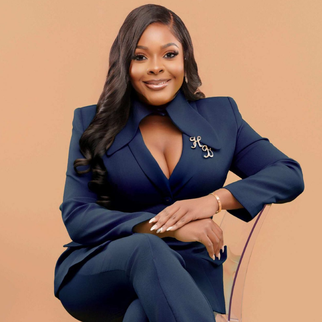 Hope Brown sitting in a chair smiling at the camera. Peach colored background